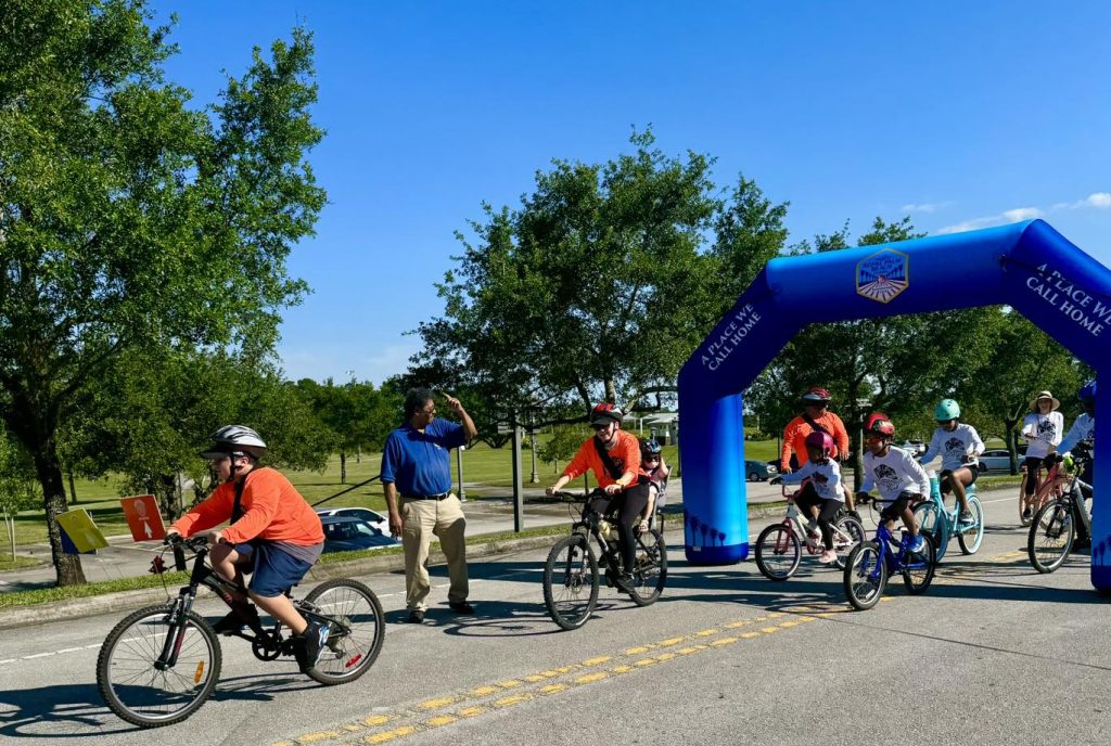 Image of children and adults crossing a bicycle ride finish line during FL bicycle month 2024